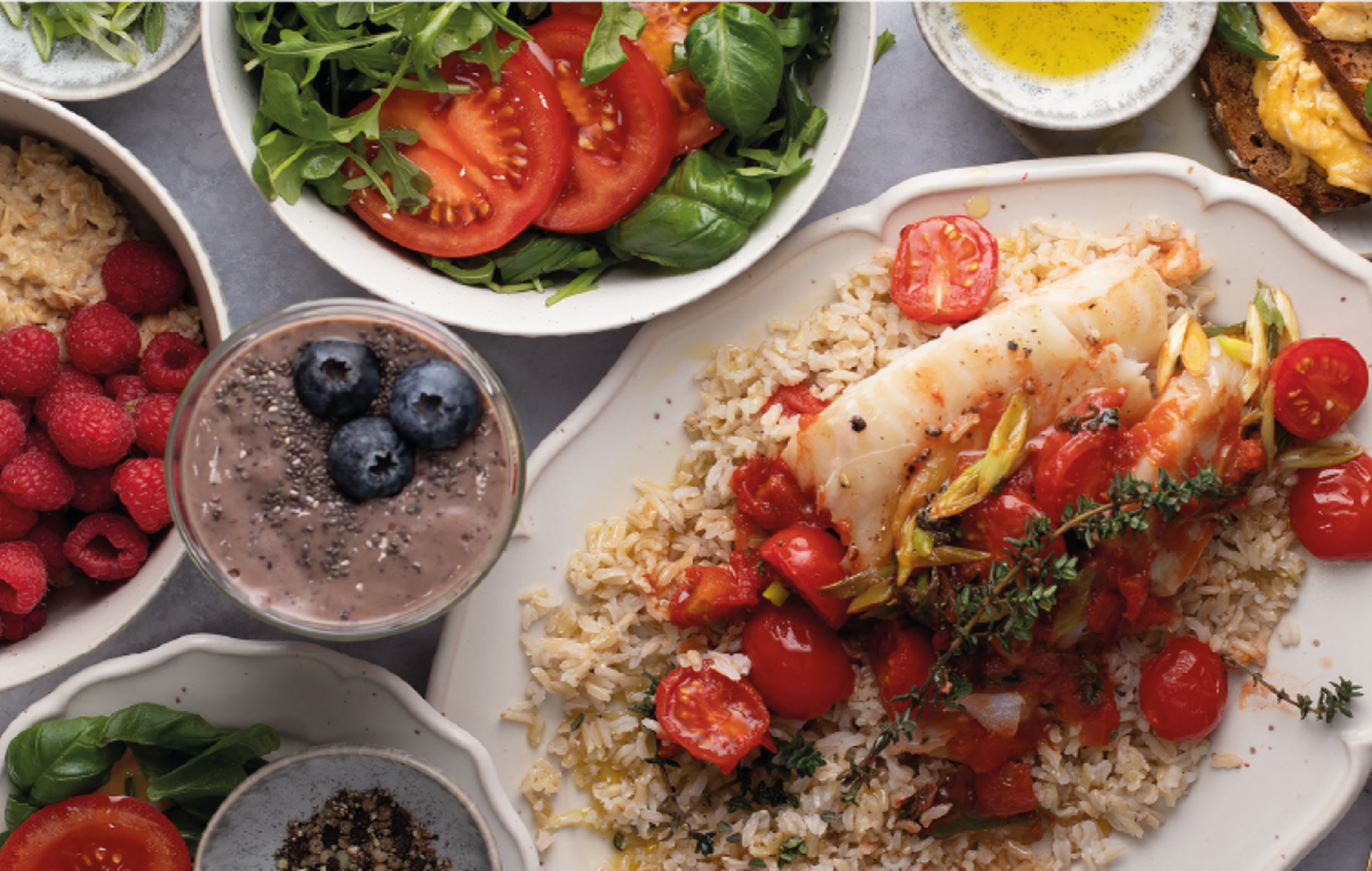 Prato colorido com arroz, peixe, tomates, salada e smoothie de frutas.