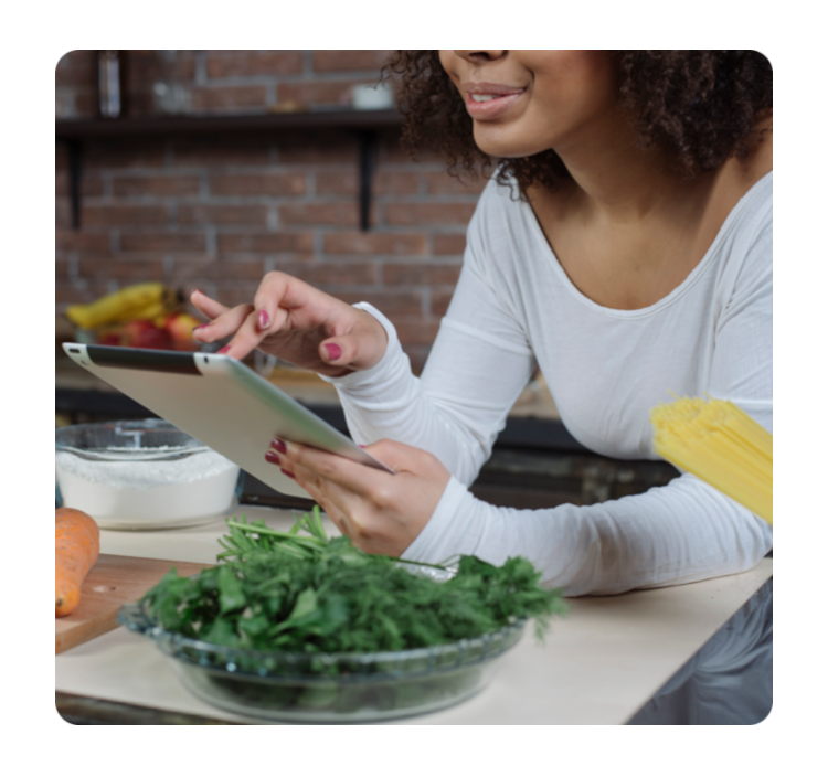 Pessoa utilizando tablet, cercada por ingredientes frescos